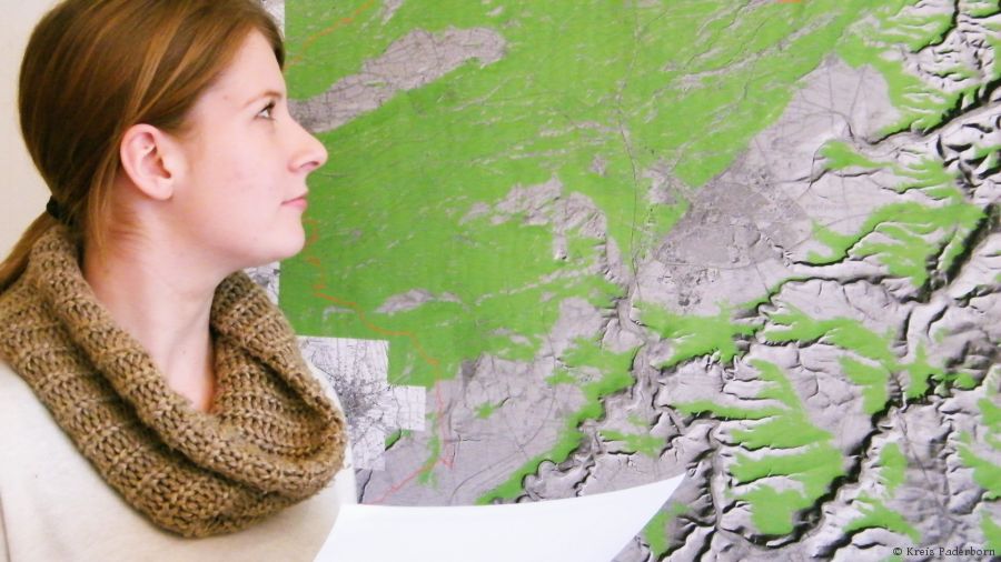 Junge Frau steht vor einer topographischen Karte © Kreis Paderborn Junge Frau steht vor einer topographischen Karte © Kreis Paderborn